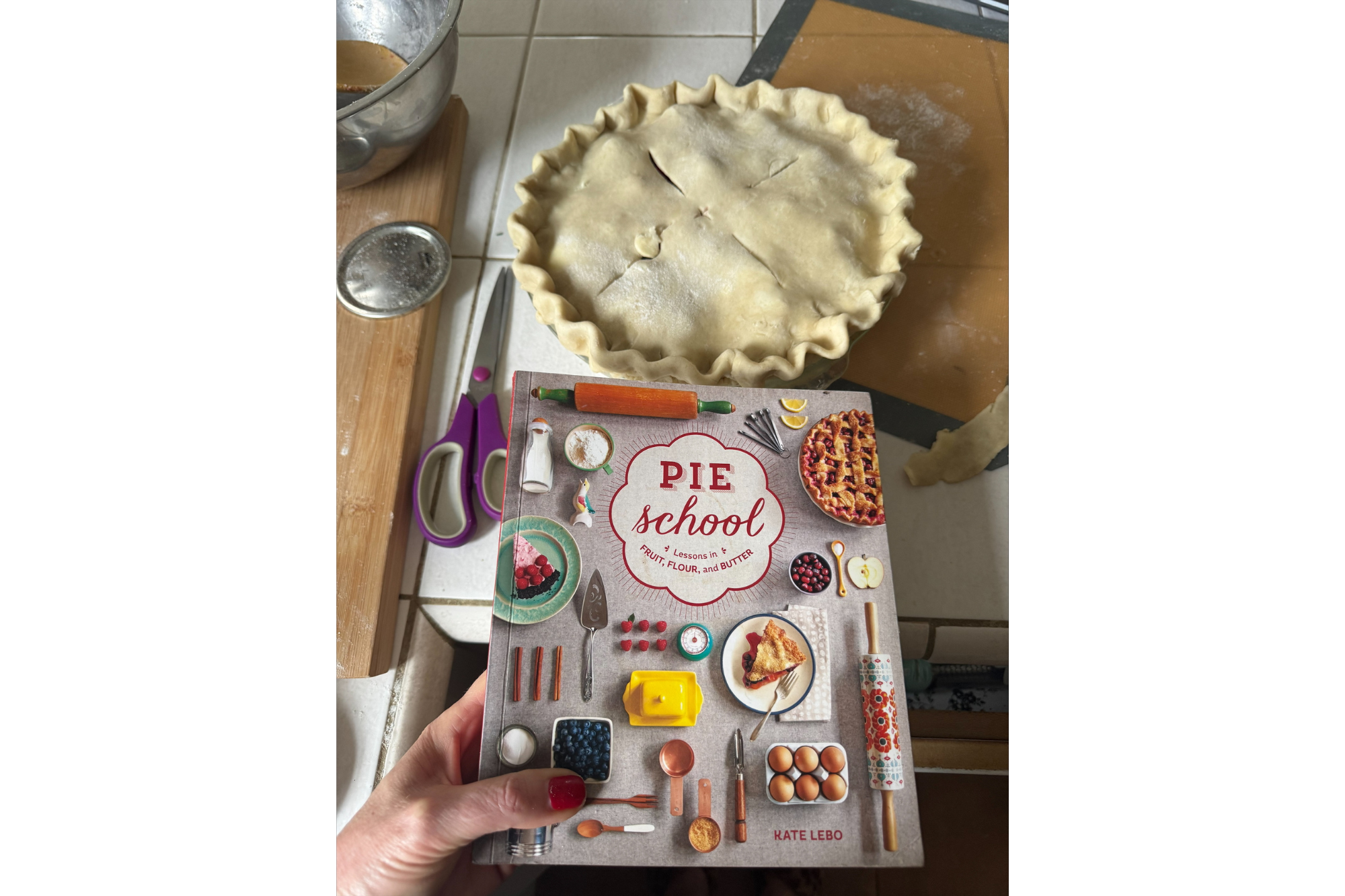An unbaked pie on a counter with a cookbook in the foreground