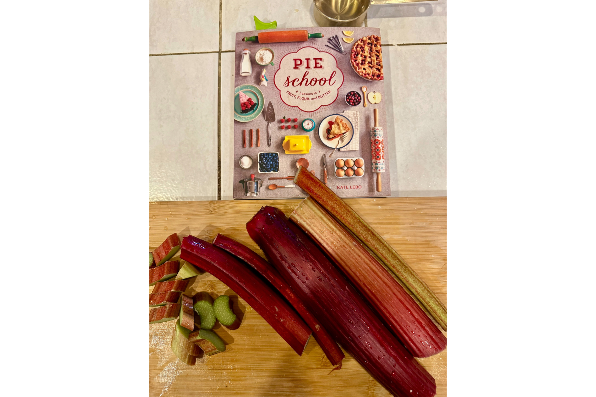Rhubarb on a cutting board with a cookbook in the background