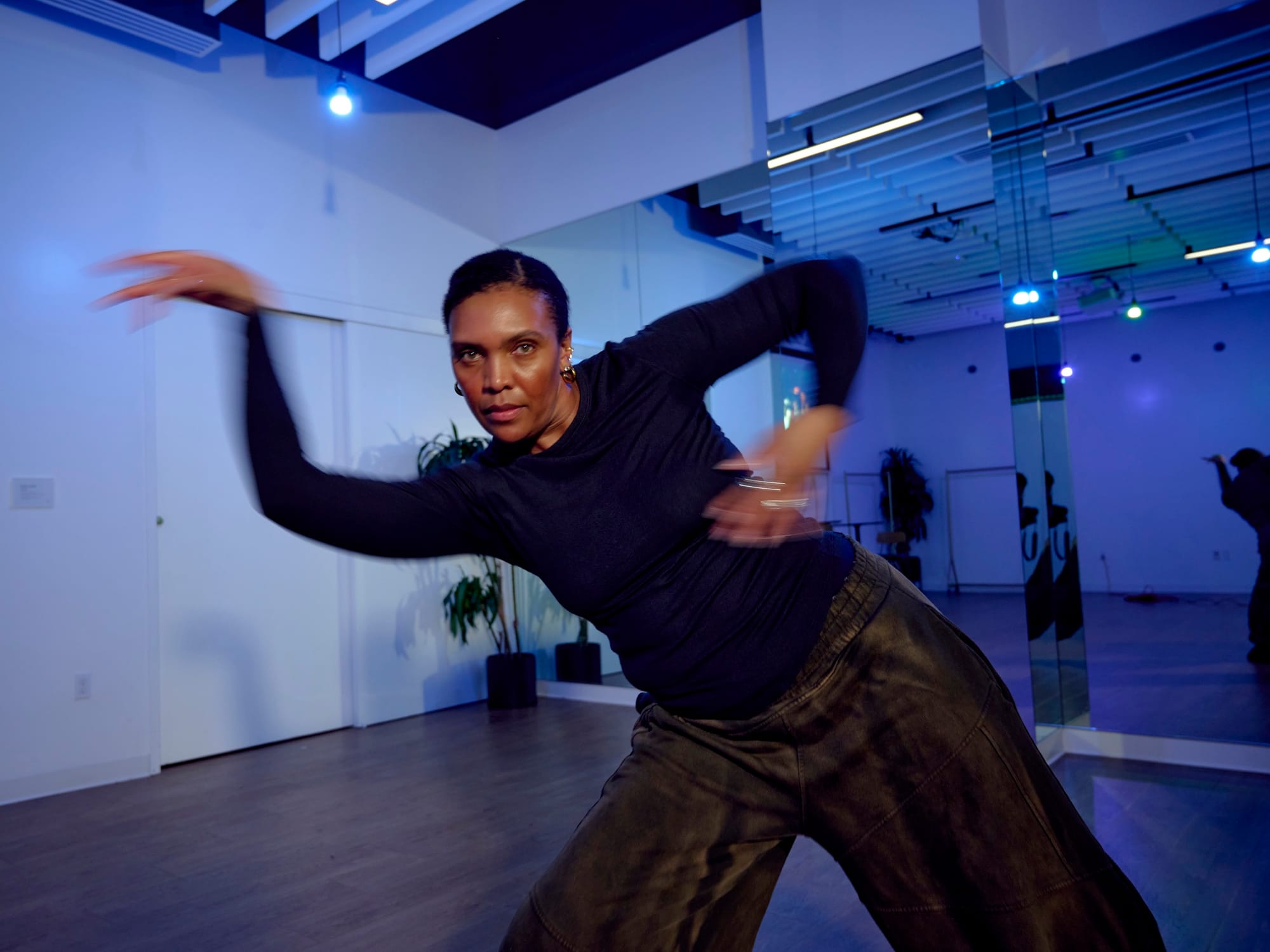 Photo of a dancer looking at the camera while in motion in a rehearsal studio