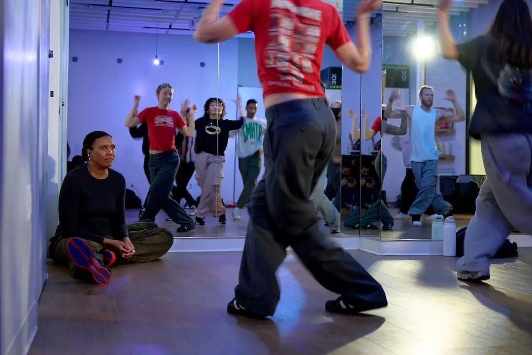 Kisha Vaughan sits on the floor of a dance studio observing students