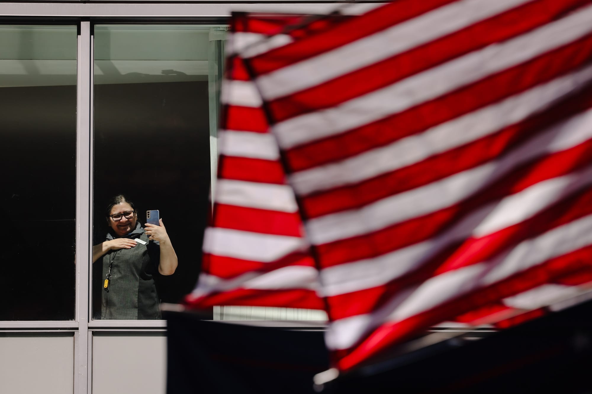 A woman looks out of a window, holding her phone, to watch the protesters in Downtown Seattle