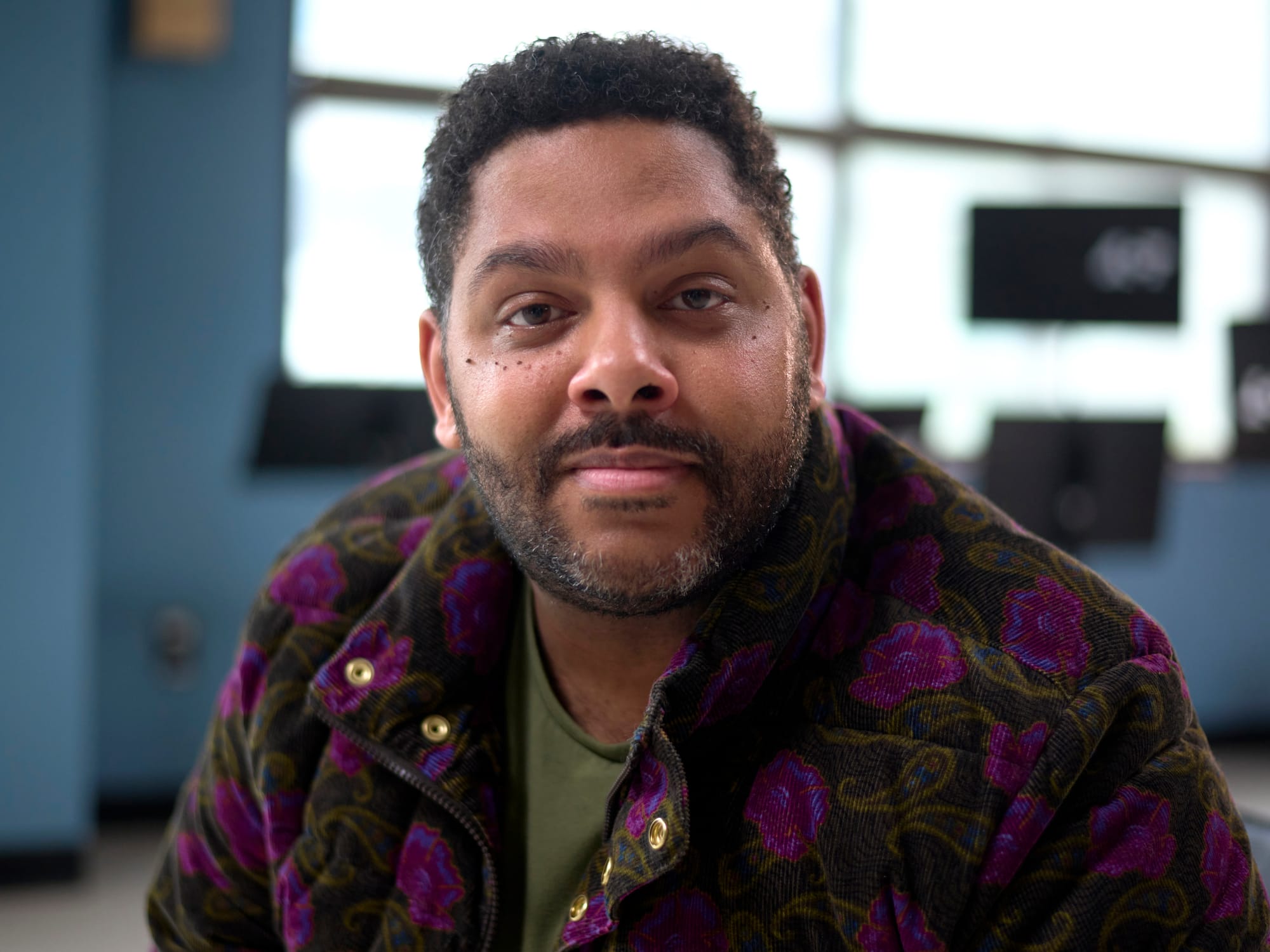 A bearded man in a purple patterned fleece jacket looks directly at the camera.