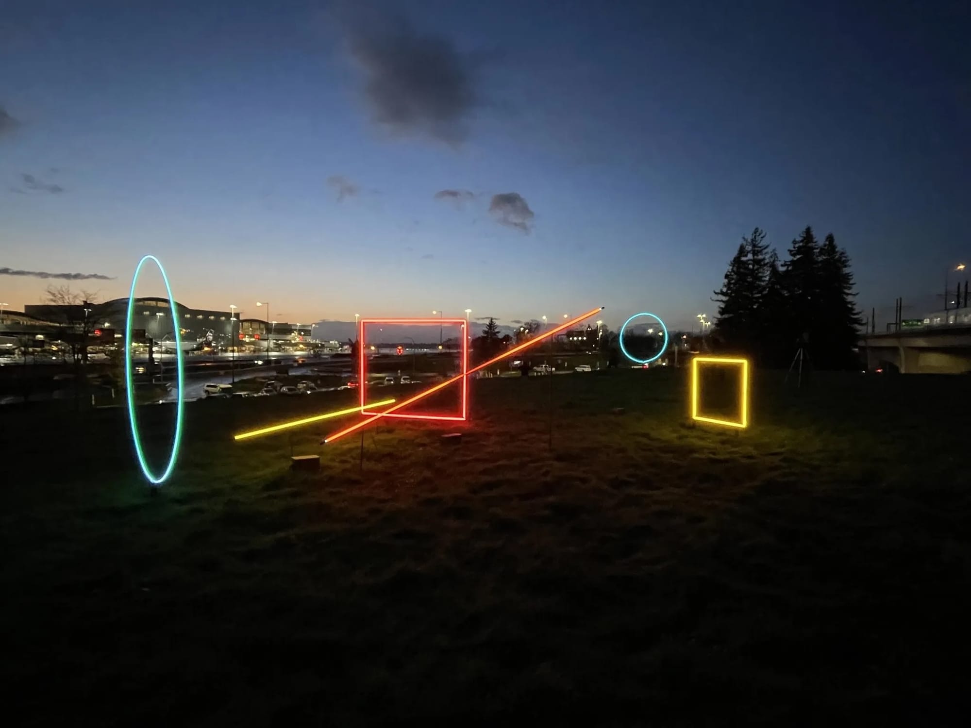 A geometric neon sculpture on a hillside at night