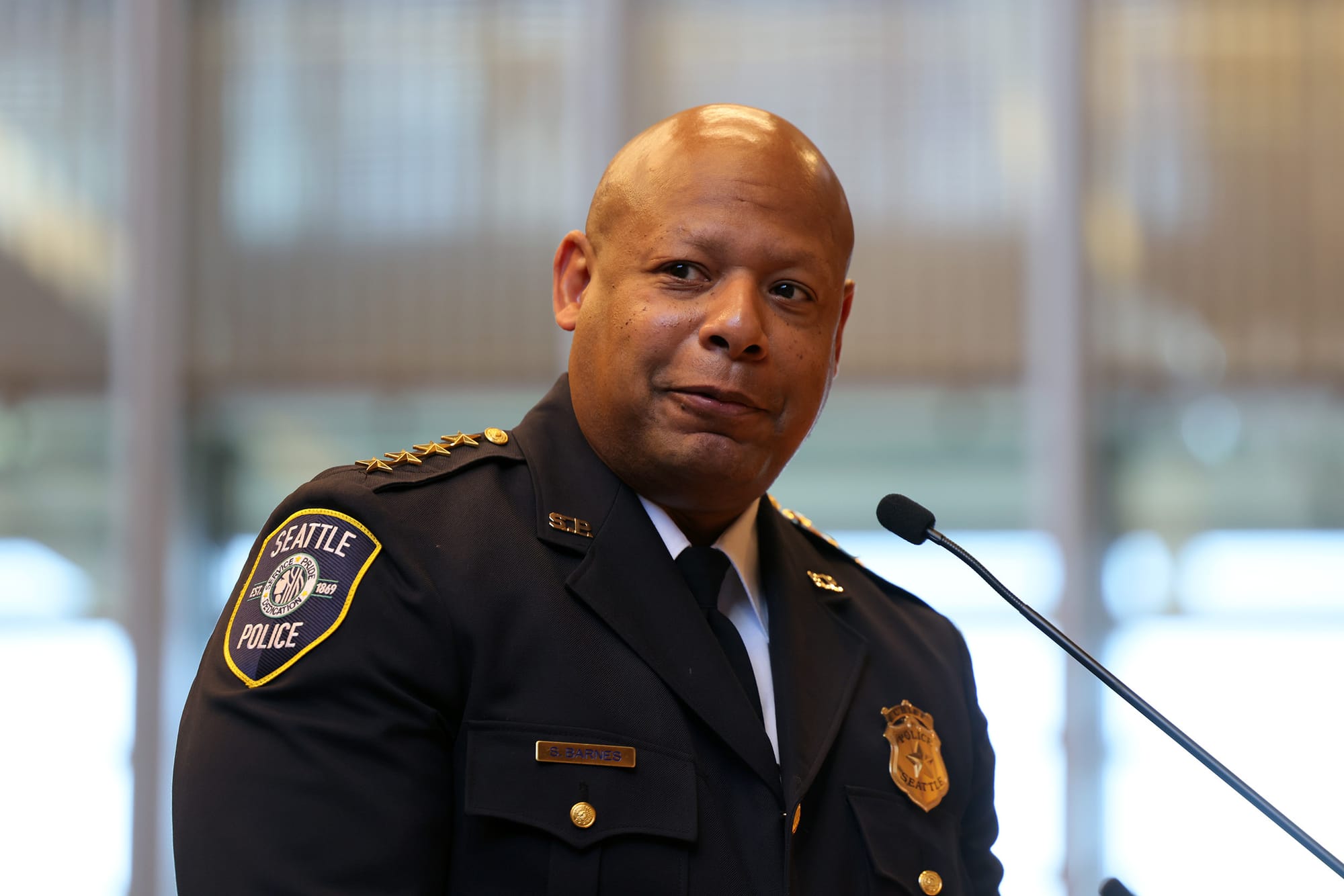 a black man in a police uniform stands at a microphone