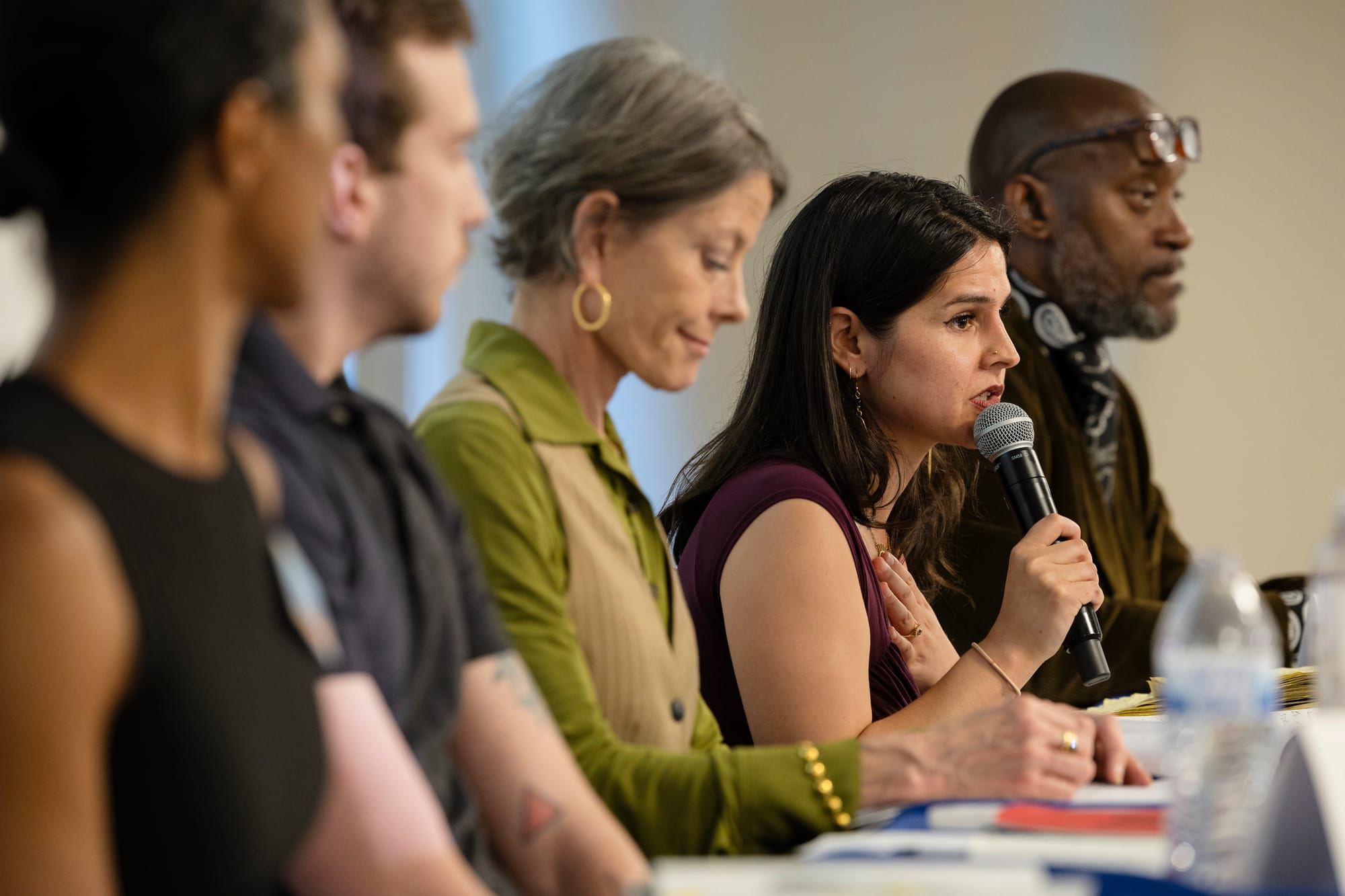 a black woman, white man, white woman, latina woman, and black man sit facing an audience behind a table 