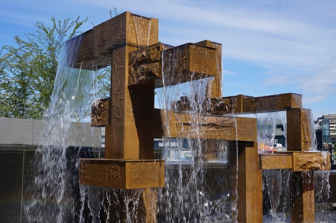 Photo of a rectilinear bronze fountain with water spilling from all angles