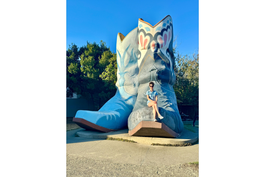Rachel Belle sits on a huge statue of cowboy boots