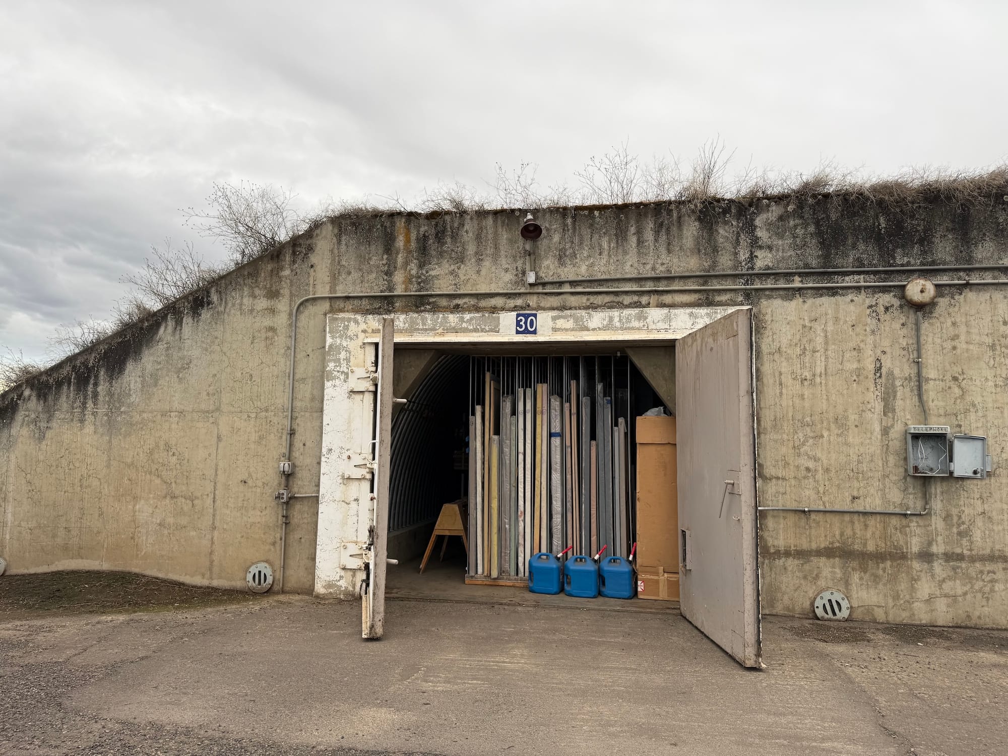 A military bunker whose doors are open to reveal stacked paintings