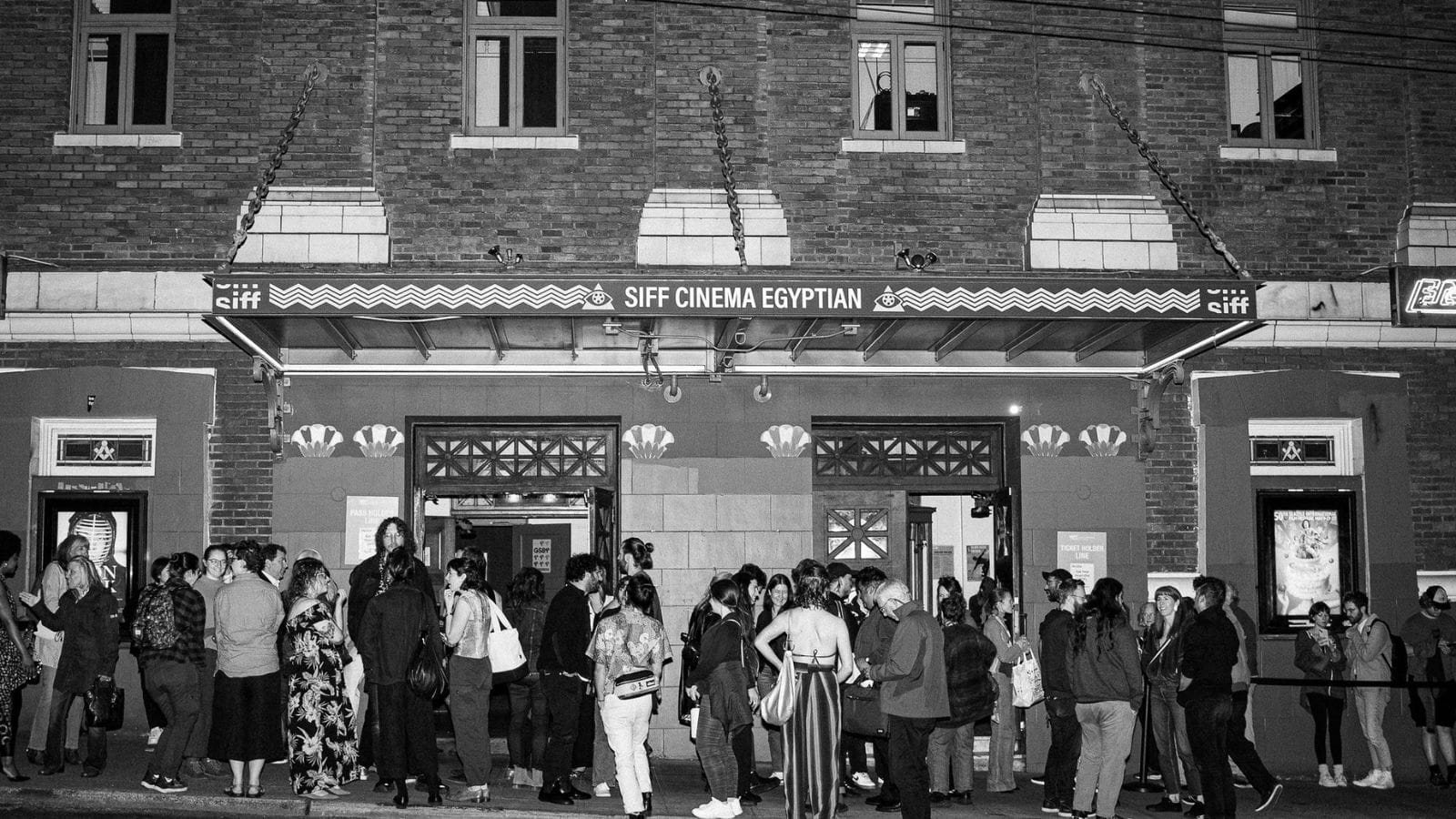 A black and white photo of a crowd lined up in front of a an old movie theater with SIFF Cinema Egyptian on the marquee
