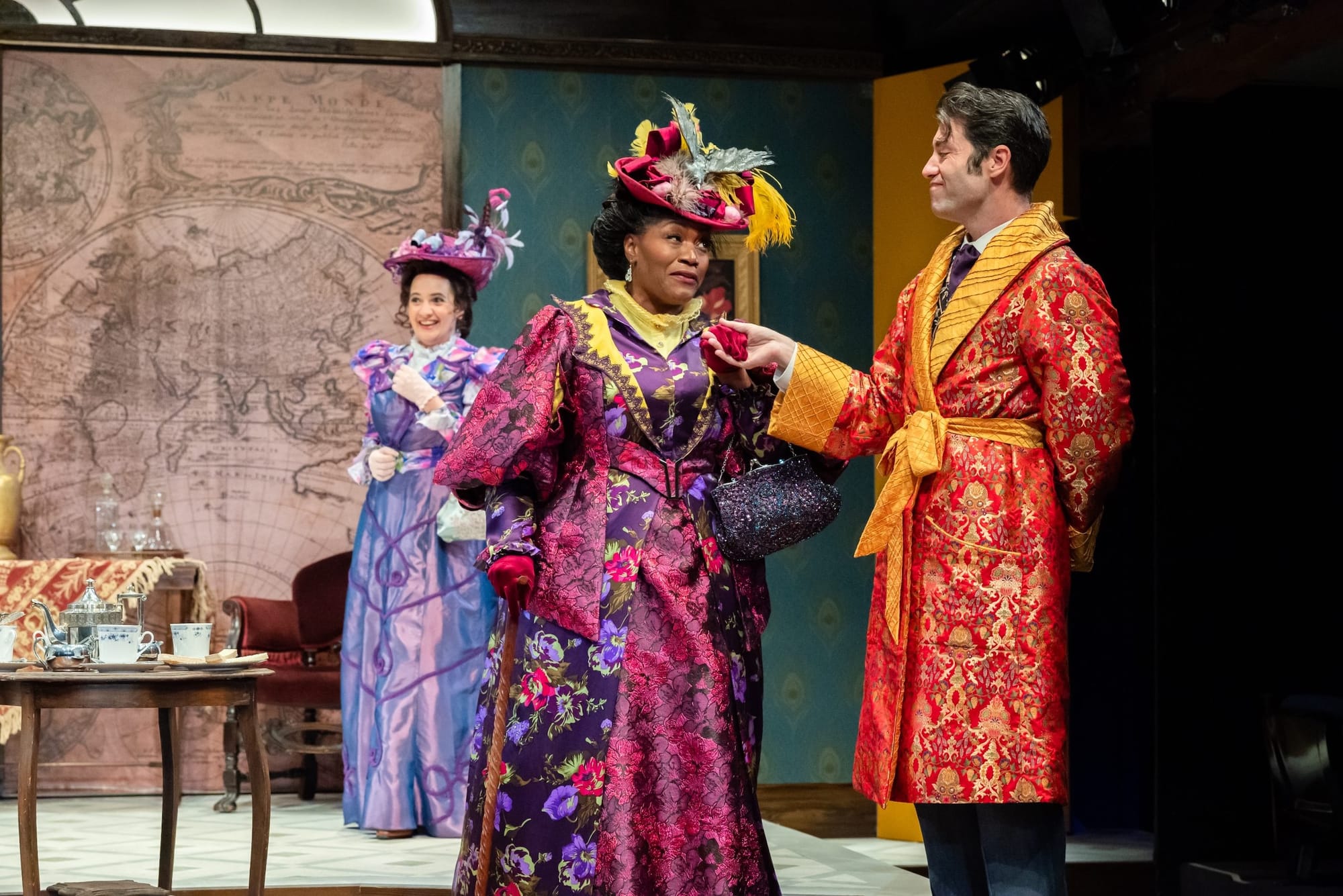 Three actors in elaborate Victorian garb on stage mid-performance