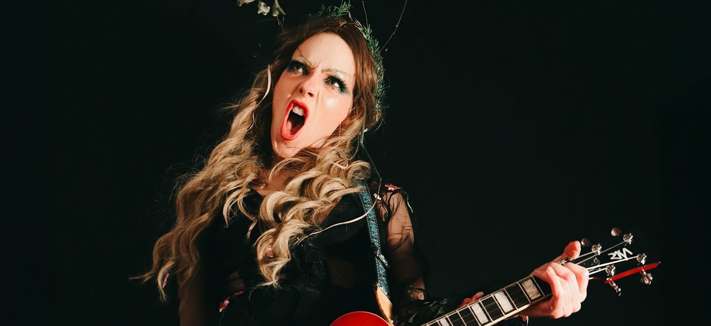 Photo of a woman with long wavy hair striking a rock pose with an electric guitar