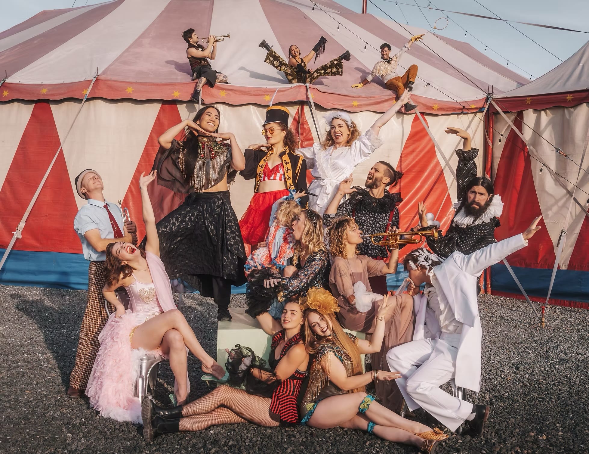 Photo of a group of circus performers posing in front of a big top tent.
