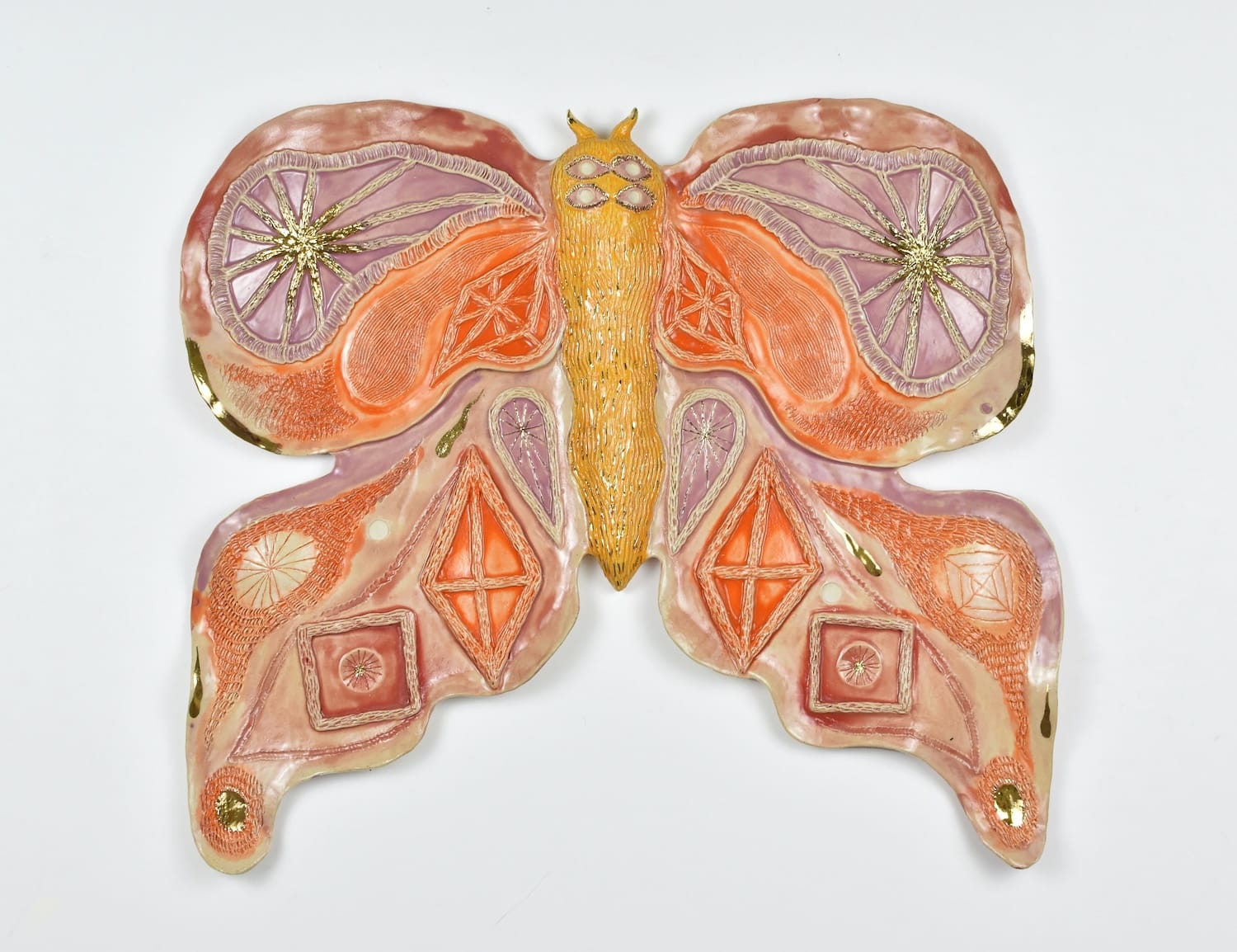 Photo of a ceramic sculpture of a moth in pink, orange and yellow