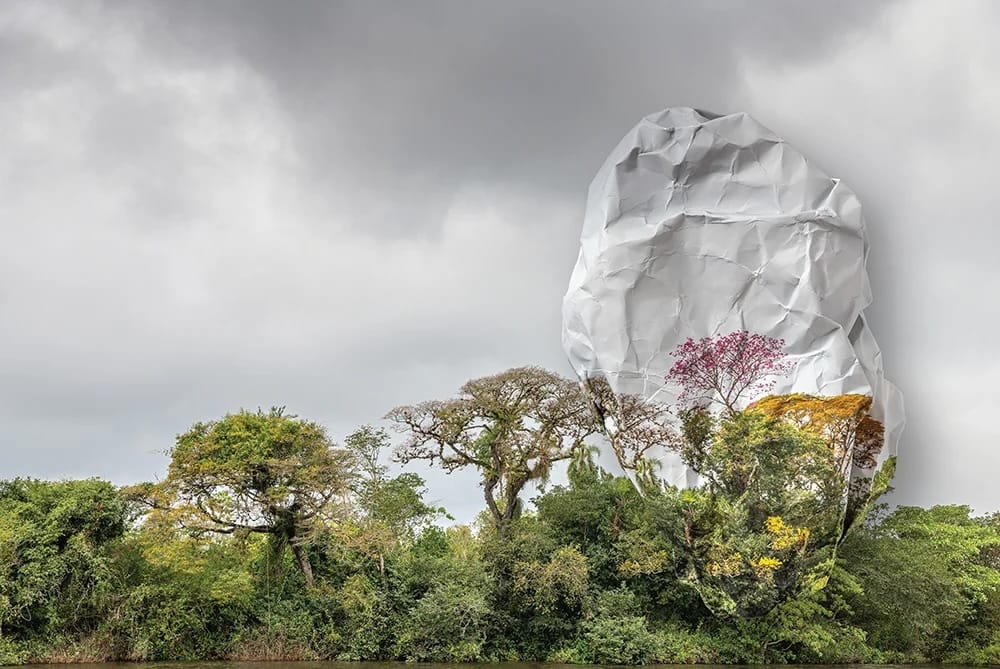 Photo of a green landscape with cloudy skies; one part of the print is deliberately bulbous and strange