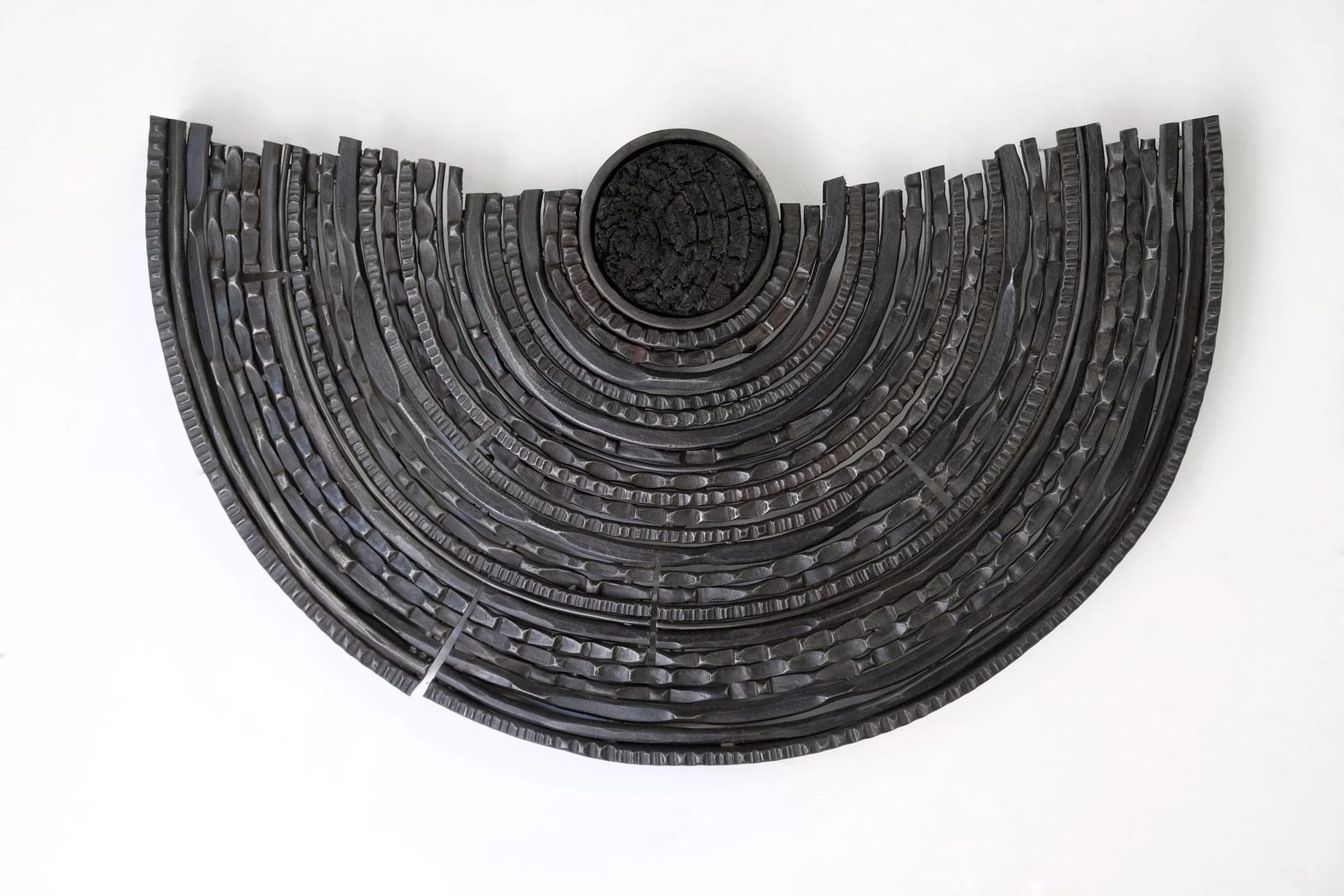 Photo of a dark gray metal sculpture that resembles tree rings.
