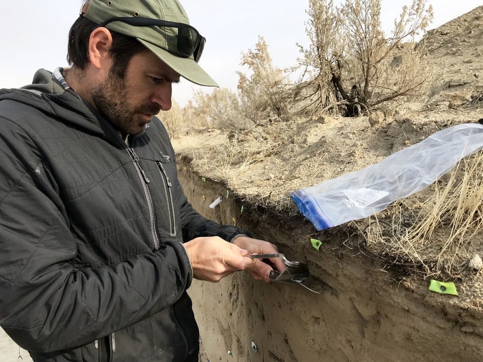 A geologist looks at flags inside a scarp