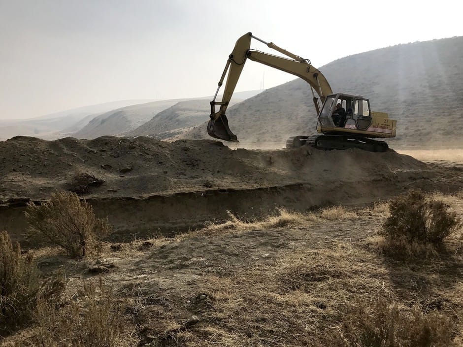 A backhoe digs near a fault scarp