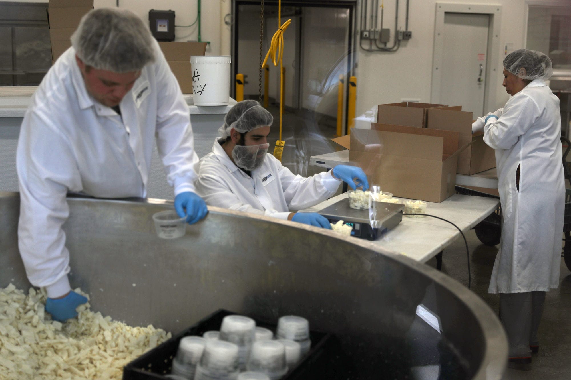 Employees package fresh cheese curds inside the plant at Appel Farms near Ferndale, Washington.