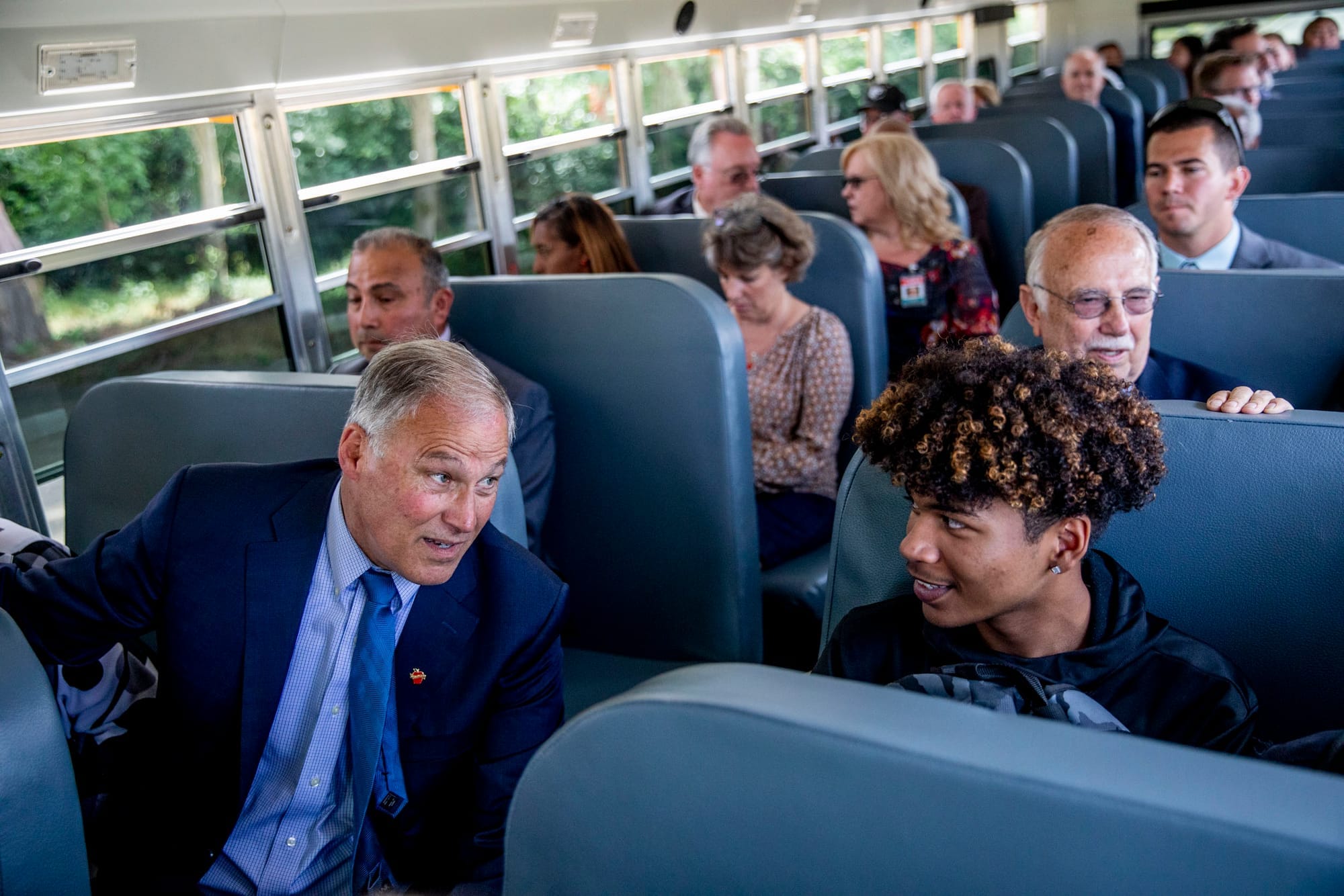 Governor Jay Inslee talks with freshman Malik Goodrum as they ride in the first electric school bus in Washington state during an event at Franklin Pierce High School in Tacoma on June 17, 2019. (Photo by Dorothy Edwards/Crosscut)