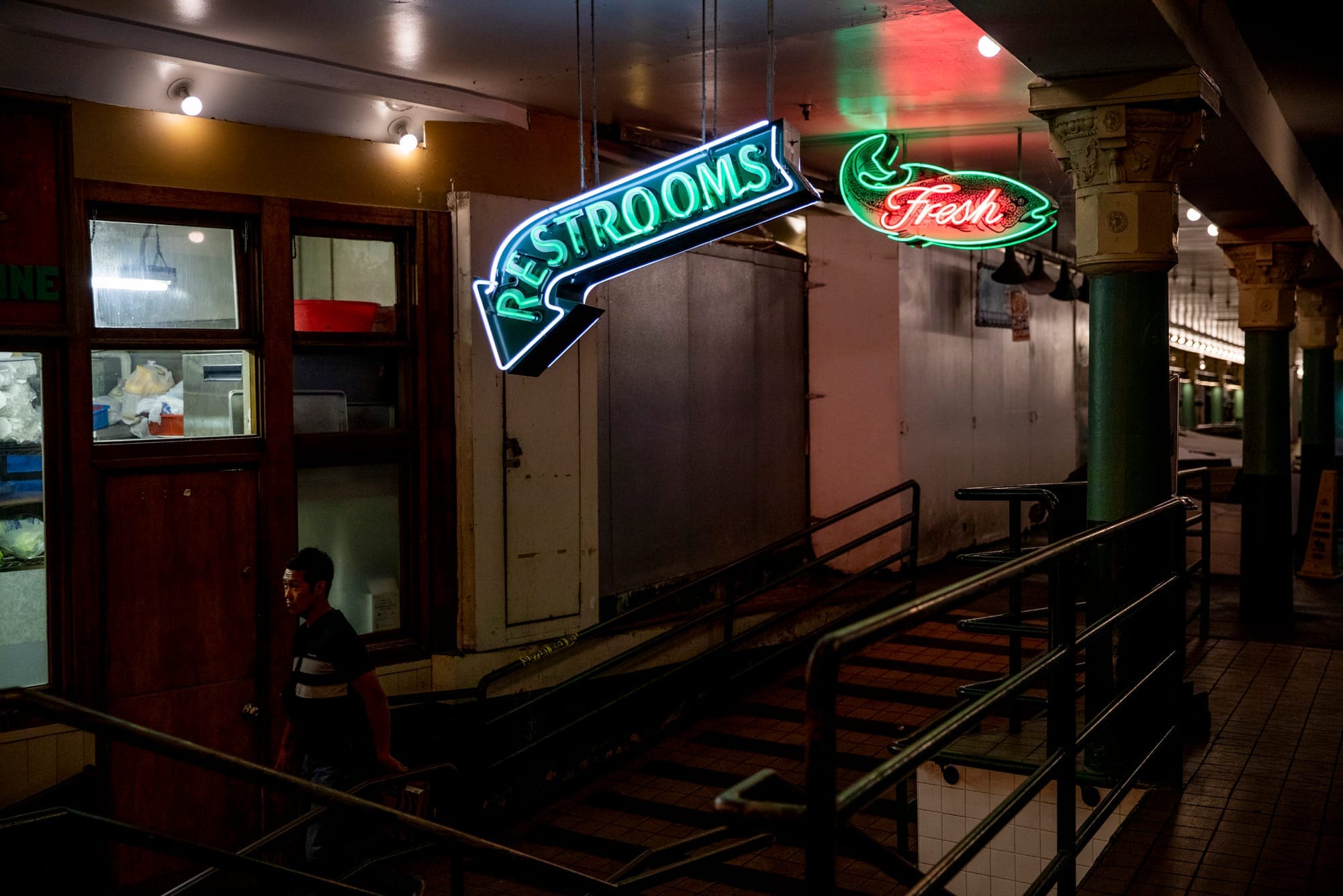 man walks under neon signs