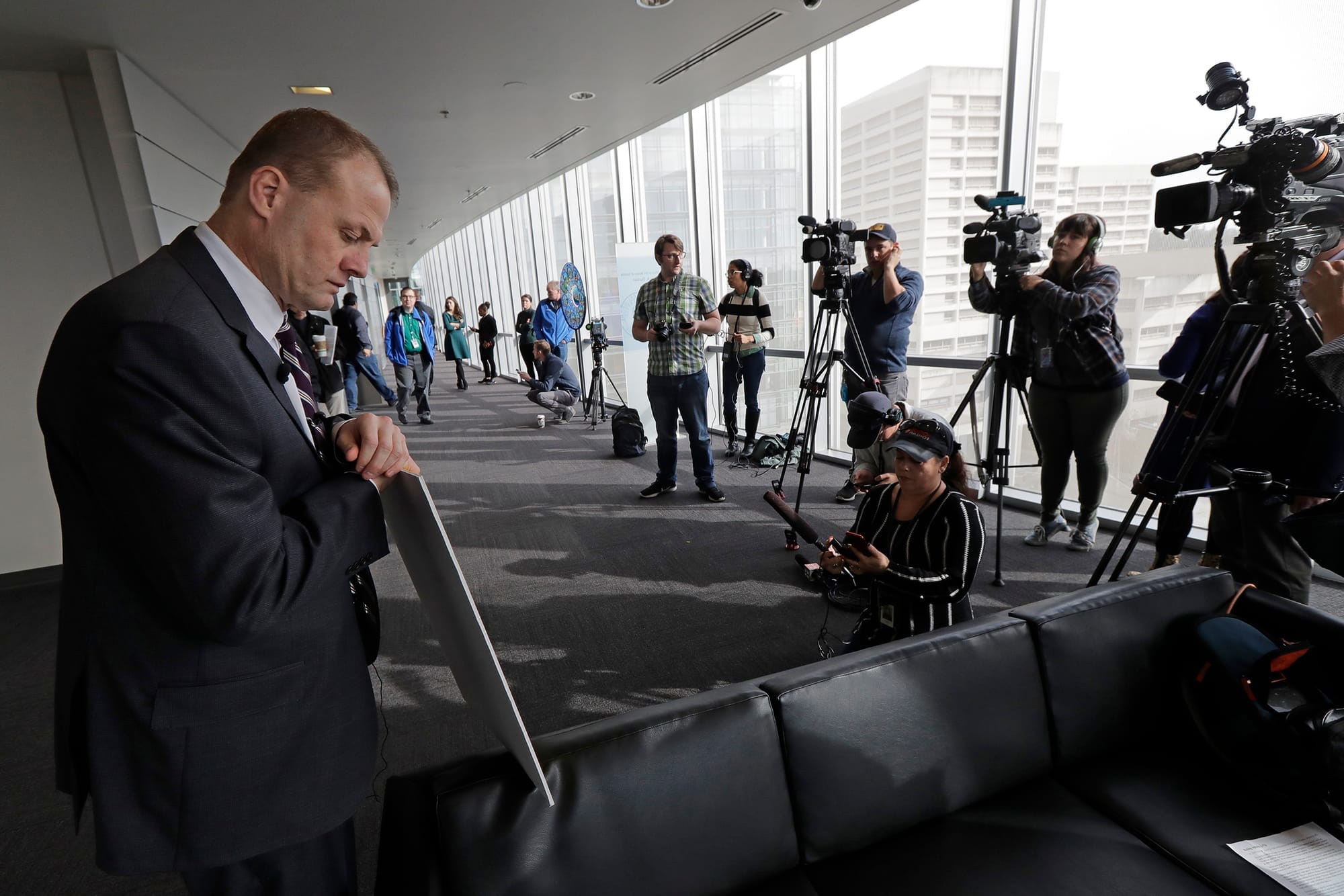 Tim Eyman holds a sign as cameras film him in city hall