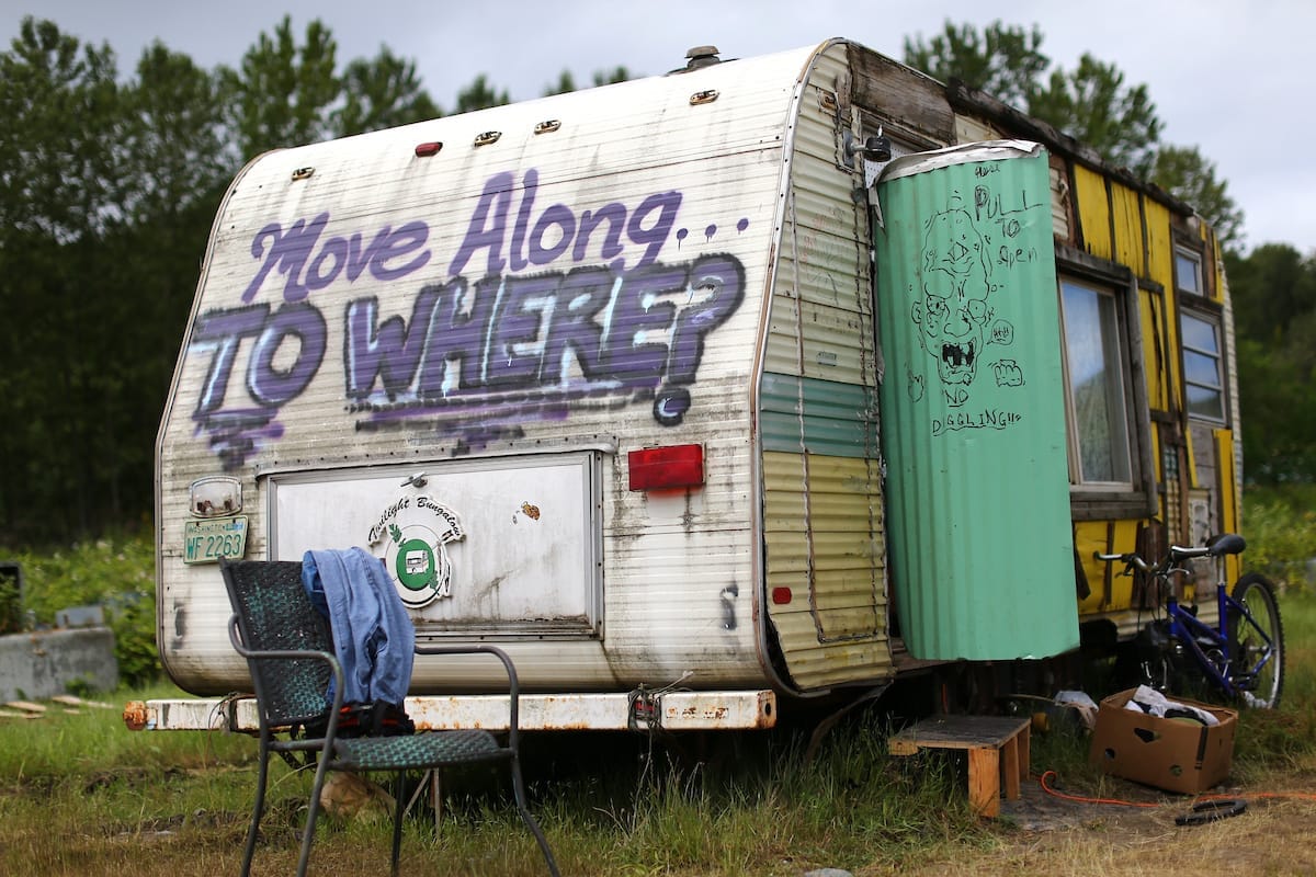 A trailer with graffiti saying: "Move Along to where?"