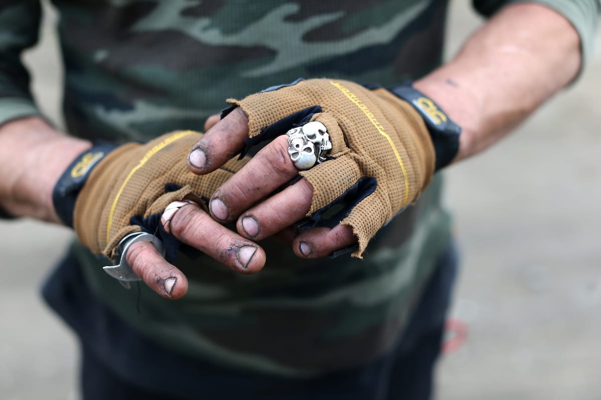 Hands of homeless man wearing yellow gloves and rings