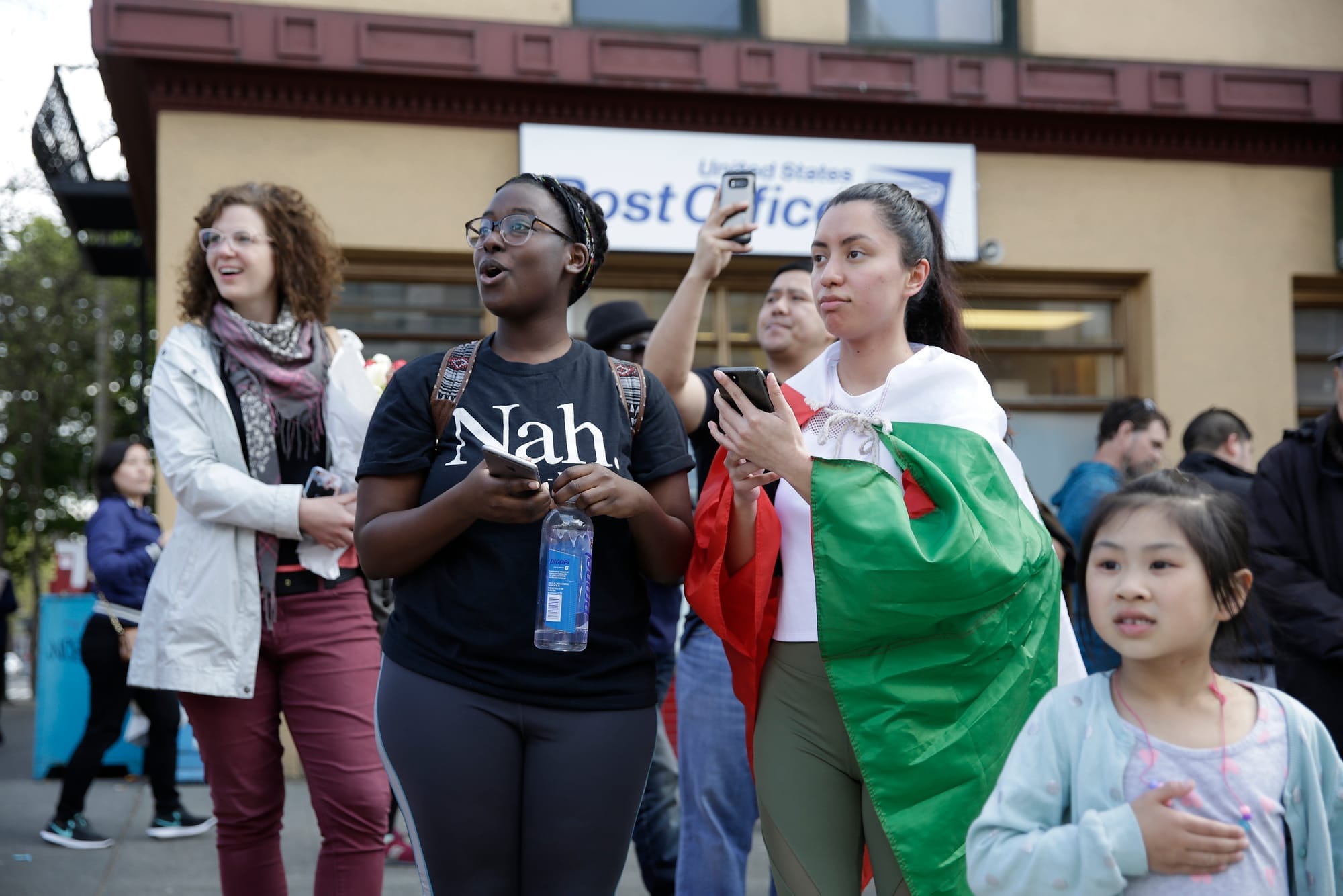 Zaria Smiley (L), 21, and Darlene Hadley, 21, both of Seattle, stop to watch before joining in the march in the International District at the annual May Day March for Workers and Immigrant Rights in Seattle, May 1, 2018. (Jason Redmond for Crosscut)