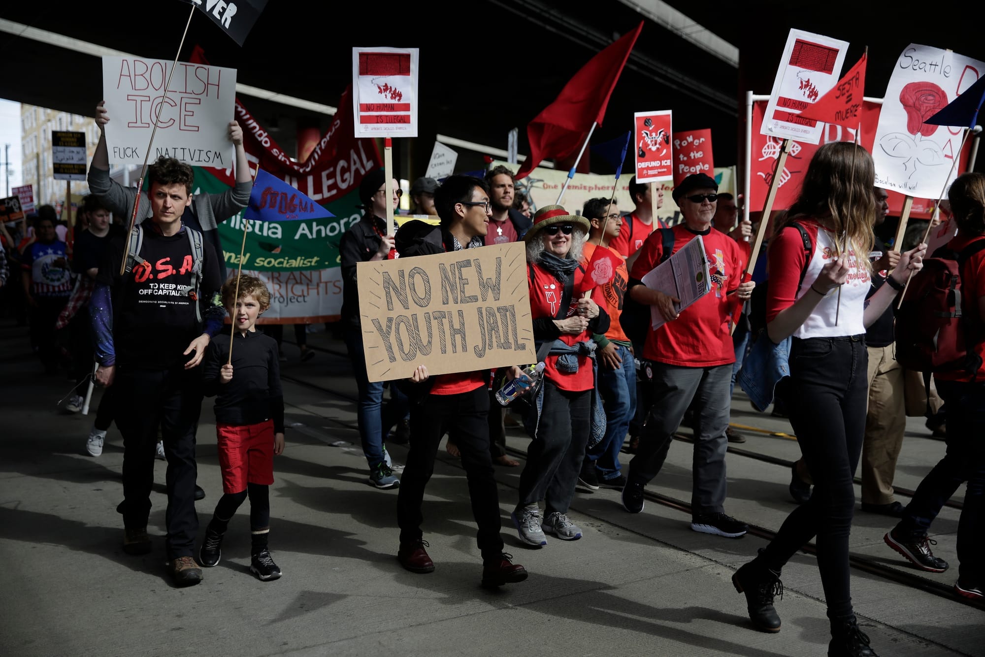 A sign protesting a new King County youth jail is pictured as people march down South Jackson Street during the annual May Day March for Workers and Immigrant Rights in Seattle