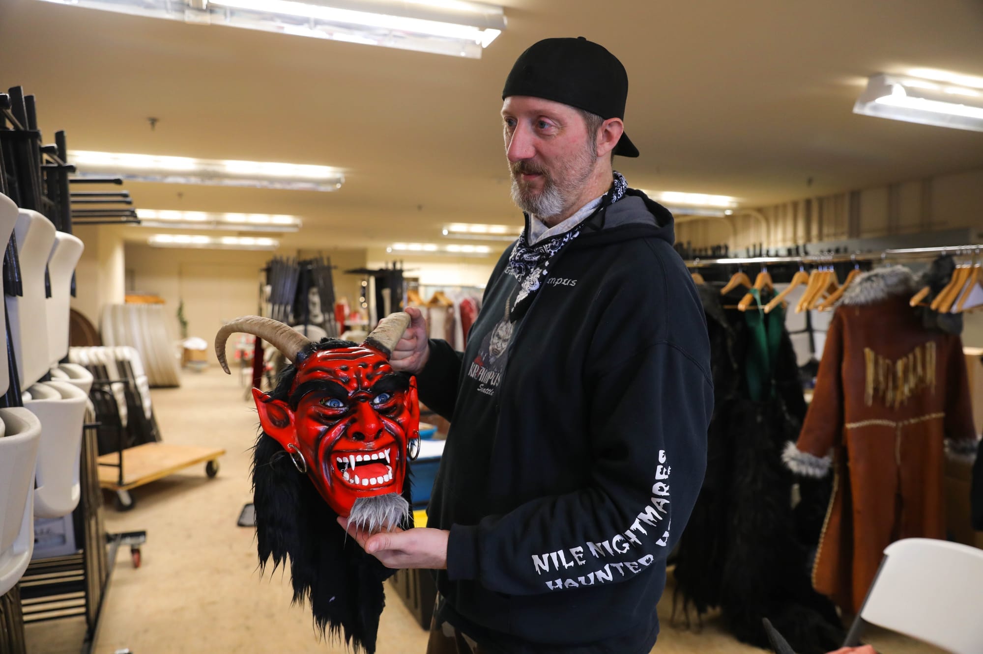 A man holds a red-horned devil mask