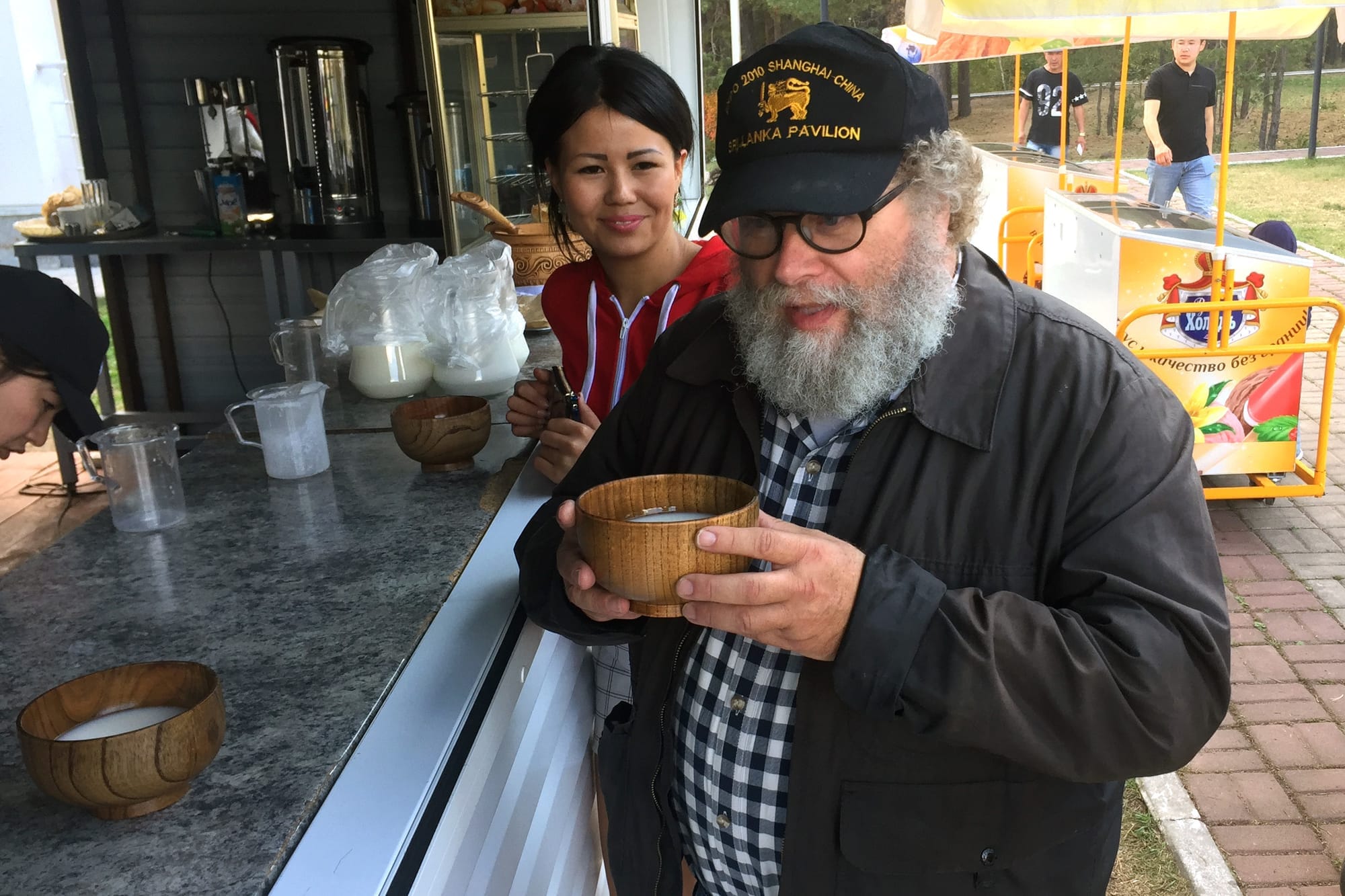 Mossback tastes kumis from a wooden bowl