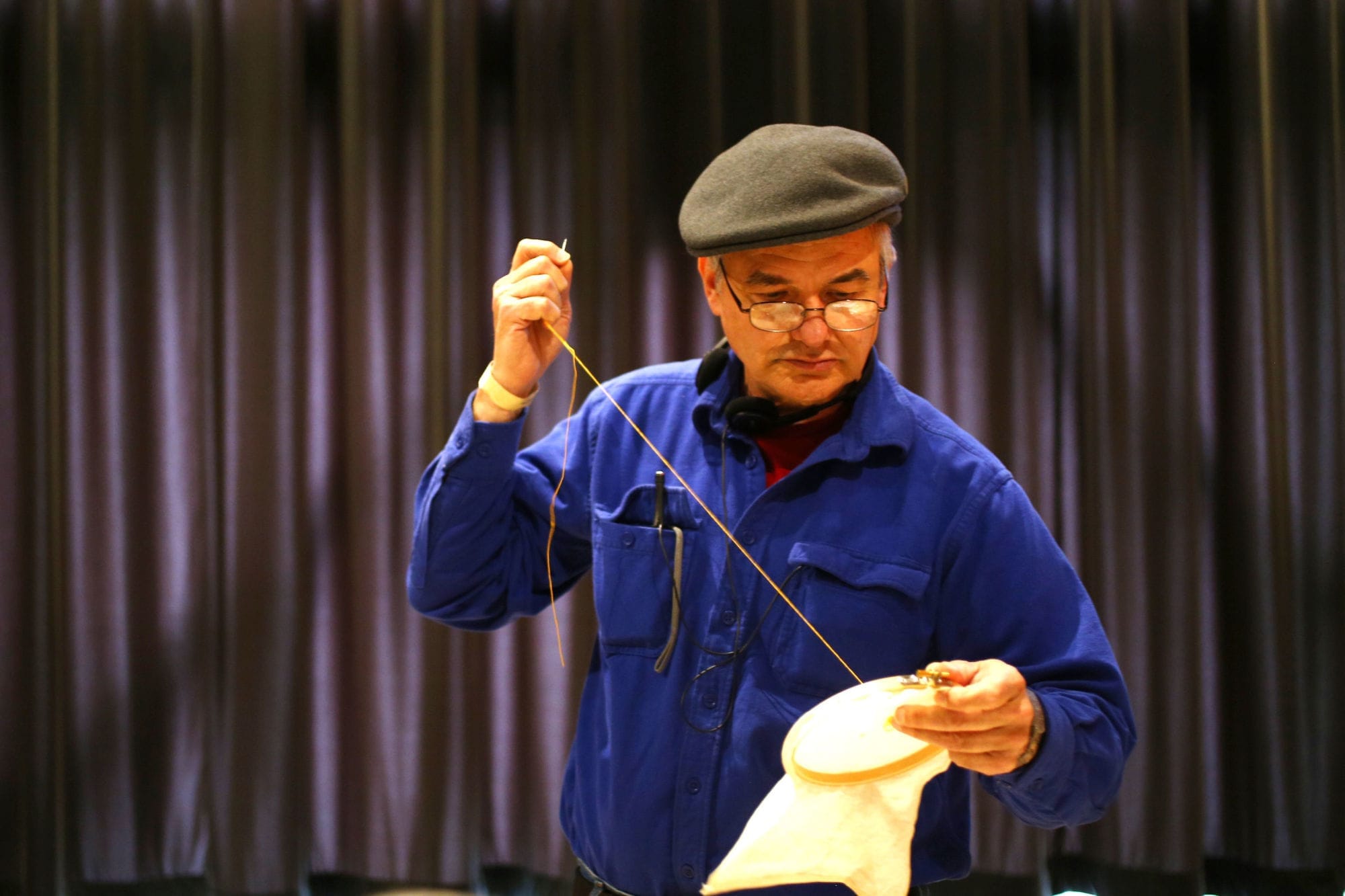 A man with blue shirt doing embroidery
