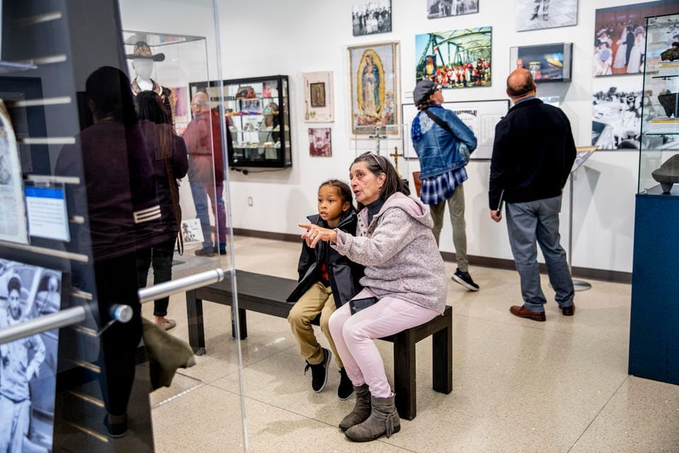 a woman shows an exhibit to her grandchild