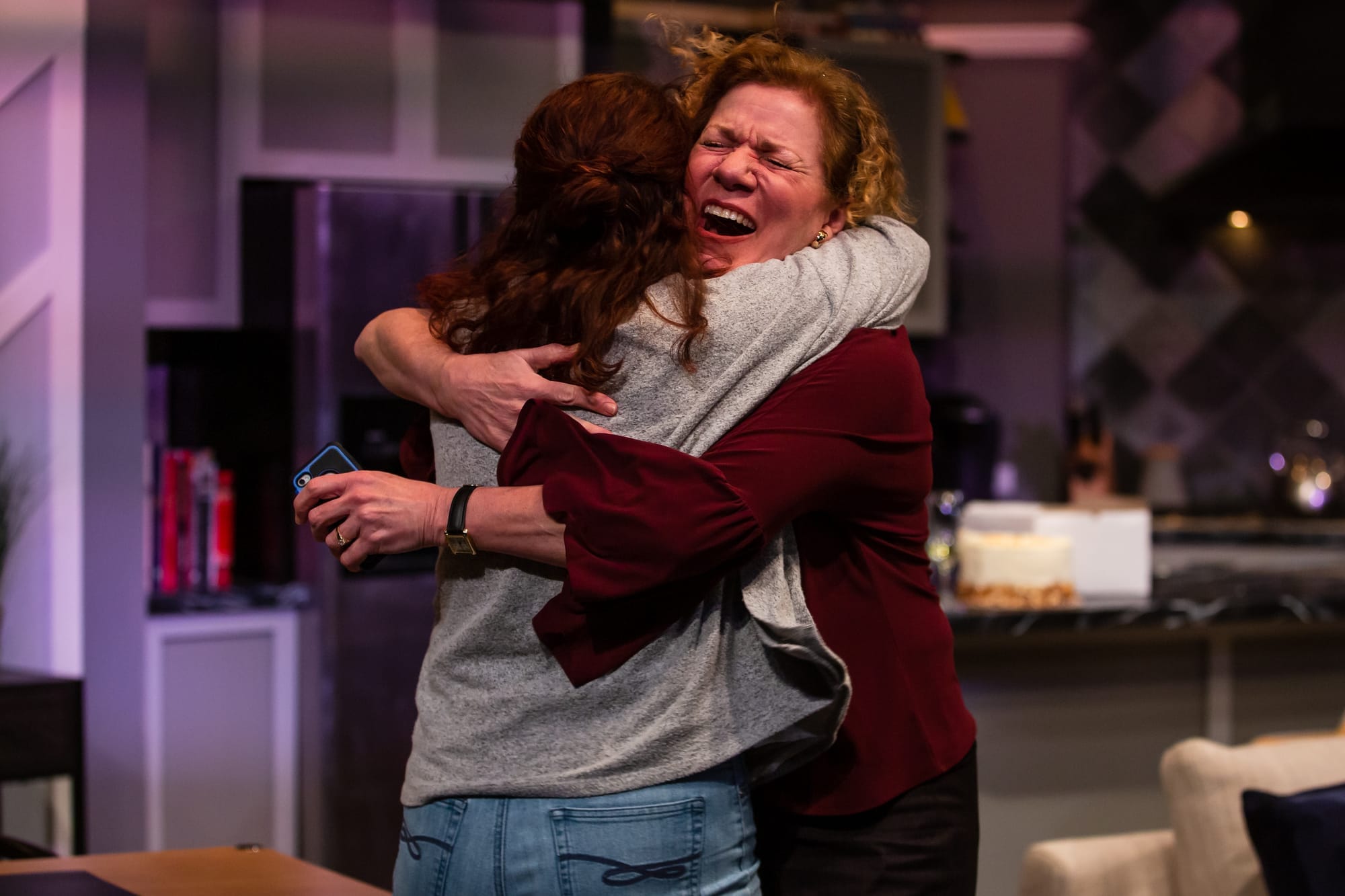 Two curly-haired women hug intensely.