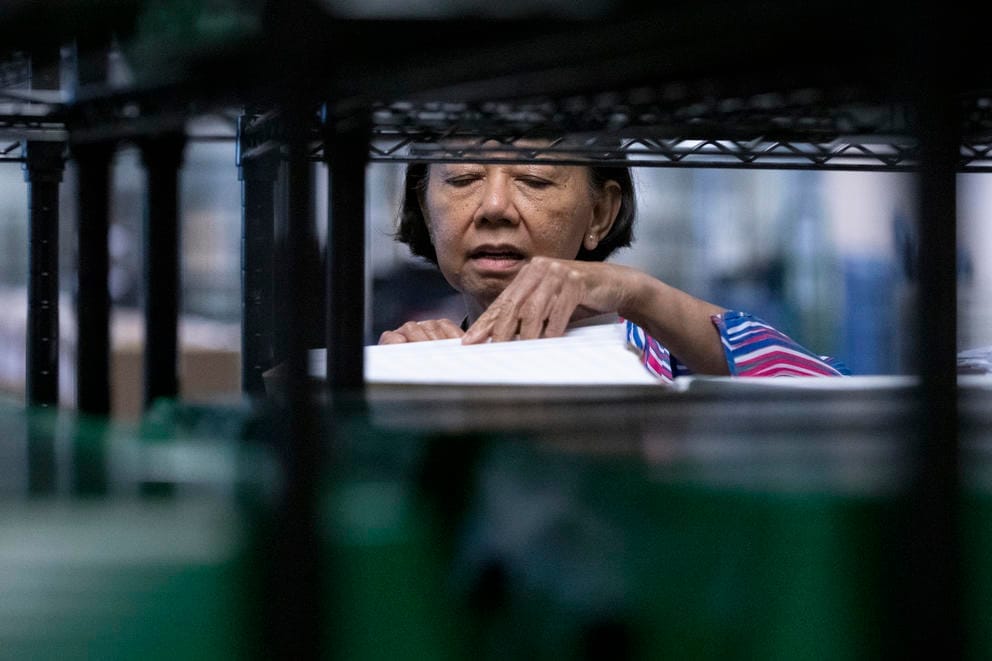 A woman looks through papers on a wire shelf