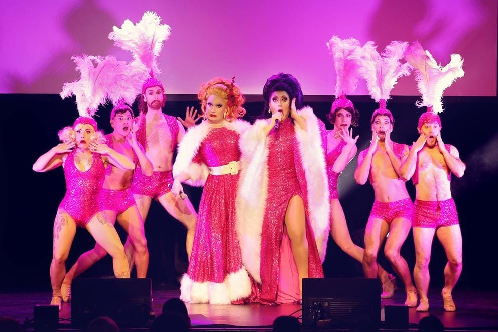 A group of performers in pink, shiny costumes
