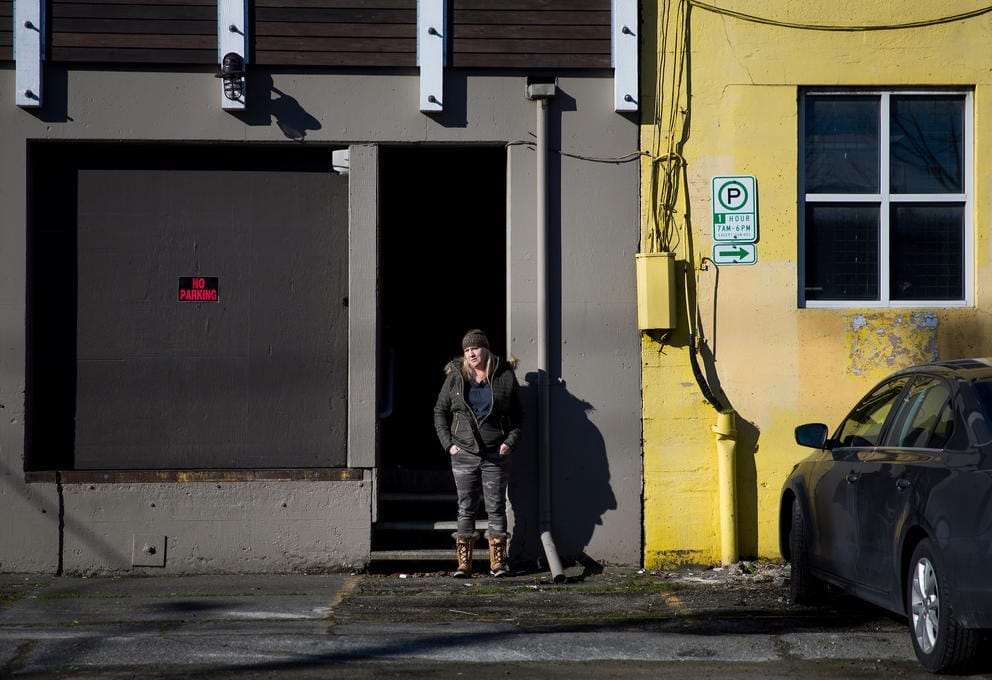 Jodi Opitz, owner of Seattle Rehearsal, stands for a portrait in front of a “no parking” sign she keeps up to make sure her business is accessible to herself and her clients 24/7 off Occidental Avenue South in Seattle