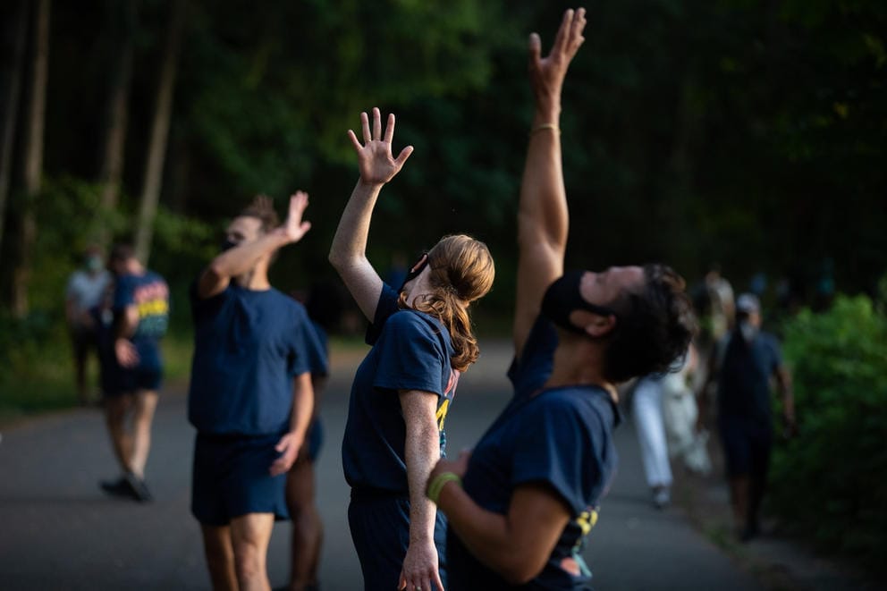 Three dancers in a row with hands in the air