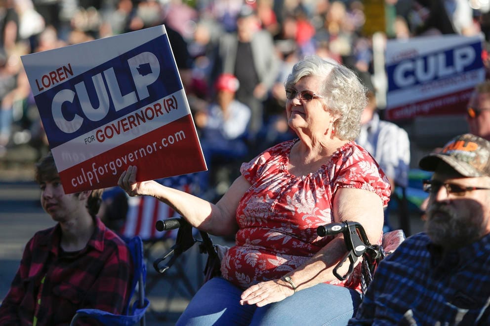 A woman holding a Culp sign sits and watches from the crowd