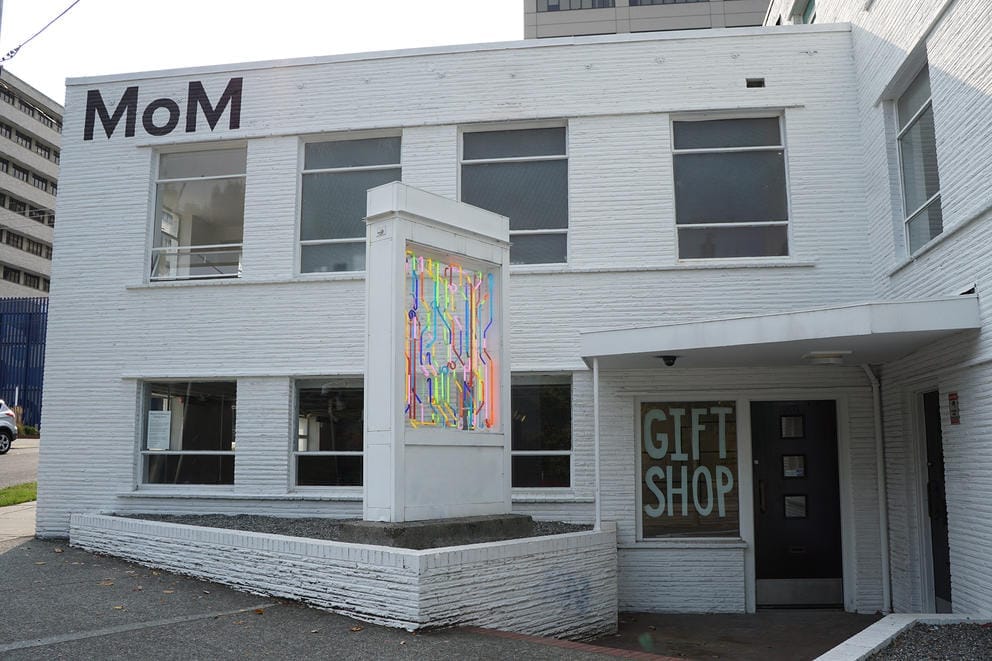 Midcentury building painted white with neon artwork in front