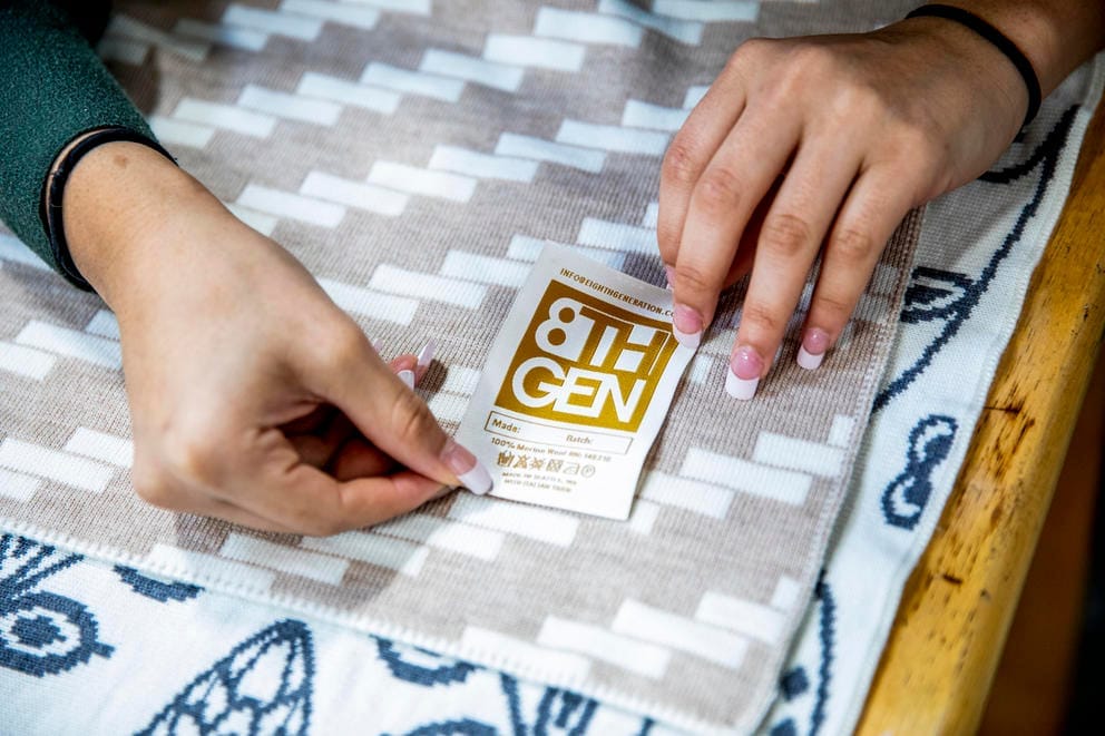 Hands on a beige and white blanket adding a golden