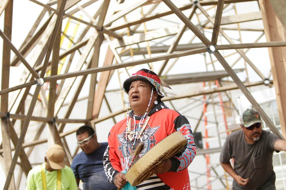 Dan Nanamkin, director of Young Warrior Society, center, leads a prayer for the land inside a geodesic dome under construction