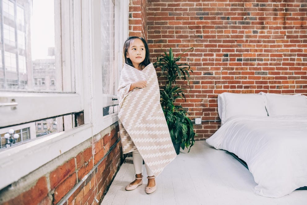 kid by window wrapped in blanket