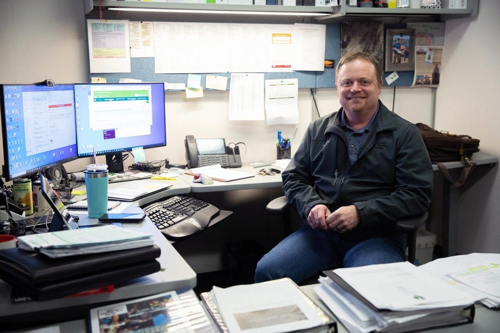 Rob Hanny sits at his desk at the Grays Harbor PUD turned away from two computer monitors and stacks of paperwork.