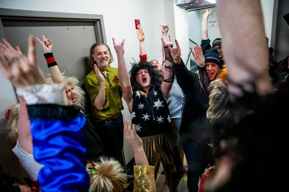 People cheer with their arms in the air in a huddle