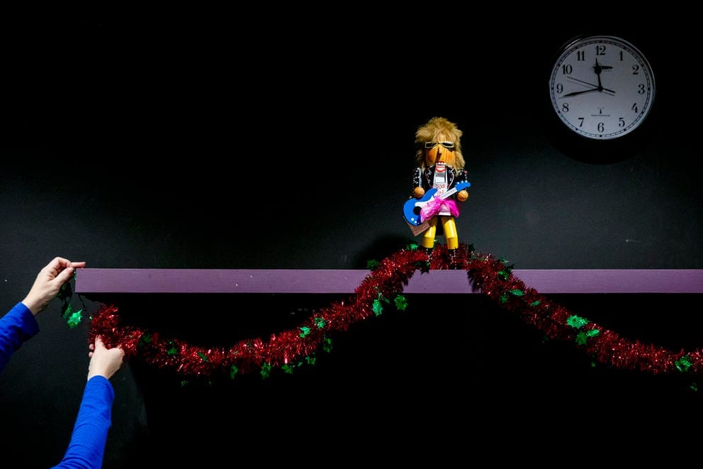 A pair of hands pin up tinsel on a shelf