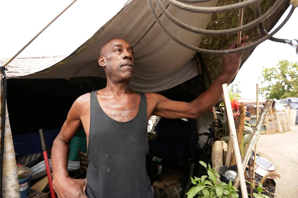 A man in front of his tent at the Camp Hope encampment