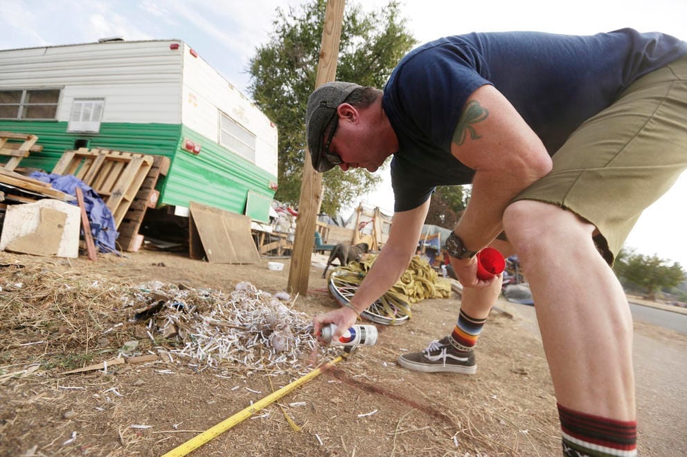 Washington State Department of transportation worker marks line for fence around Camp Hope encampment