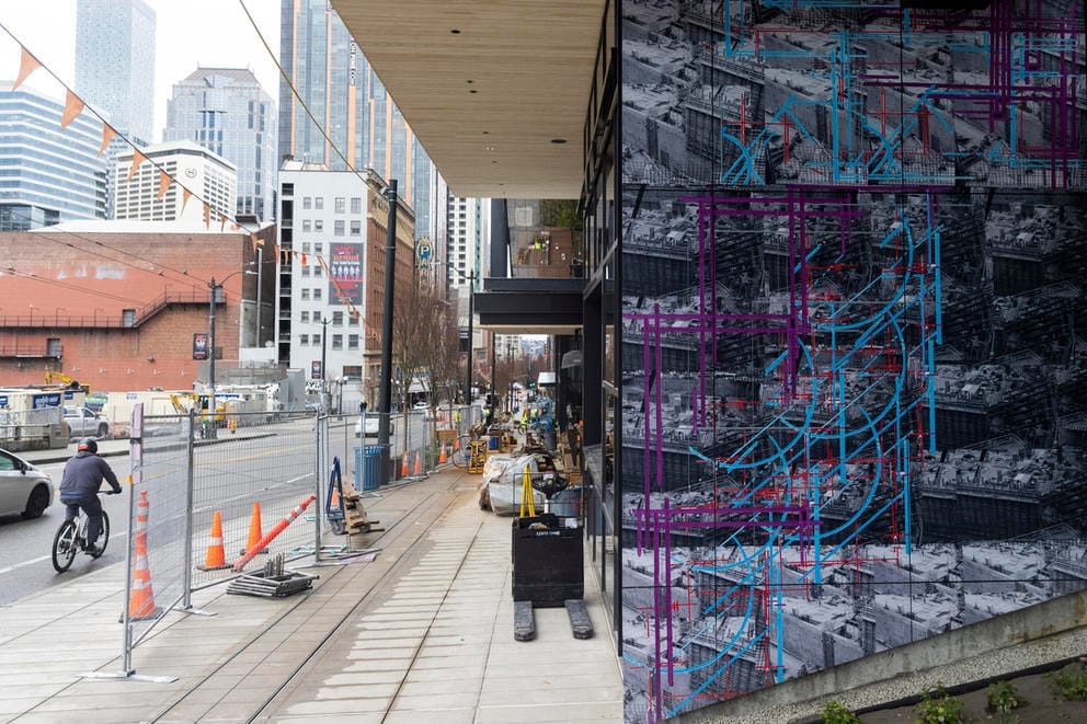 A wall featuring purple and blue stripes on black and white on the right, construction workers to its left