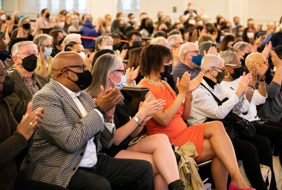 A seated crowd, fully masked